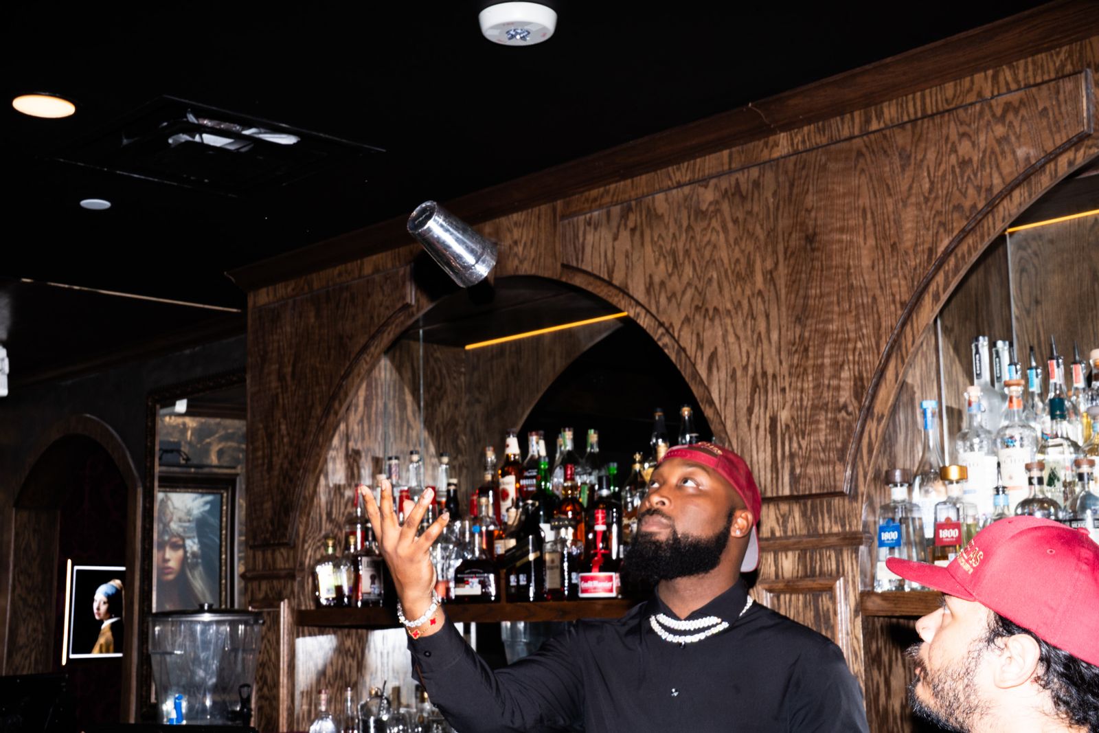 Self tossing a shaker tin into the air in front of the back bar